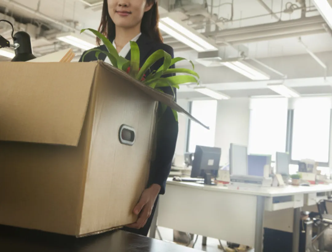 Office worker carrying a moving box with a plant